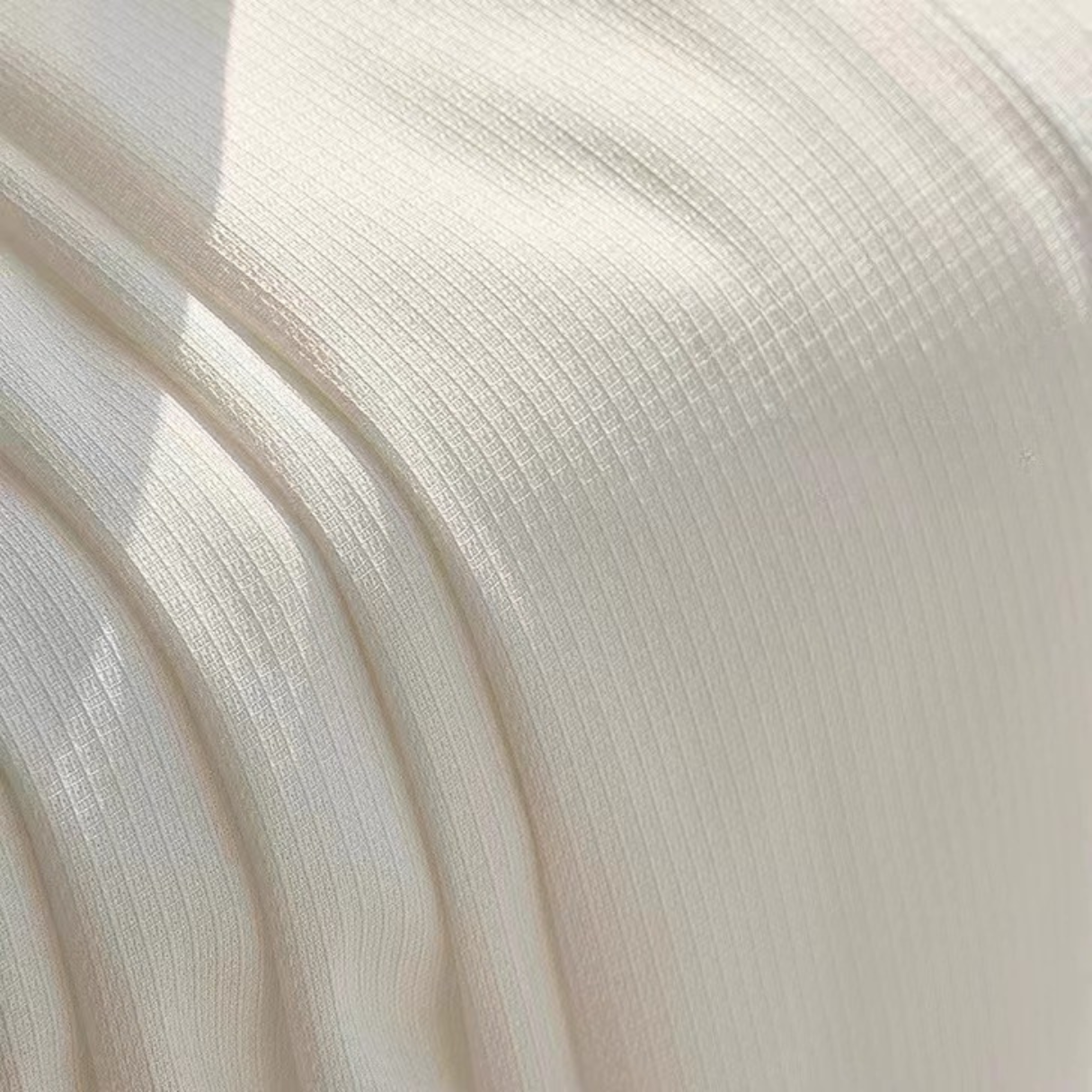 Textured white curtain fabric with soft pleats in natural light