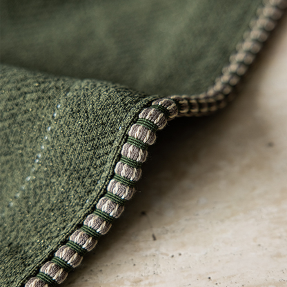 Close-up of green textured curtain fabric with detailed edge stitching, home decor textile