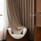 Deep walnut brown blackout curtains in a modern living room with soft armchair and sheer curtain.