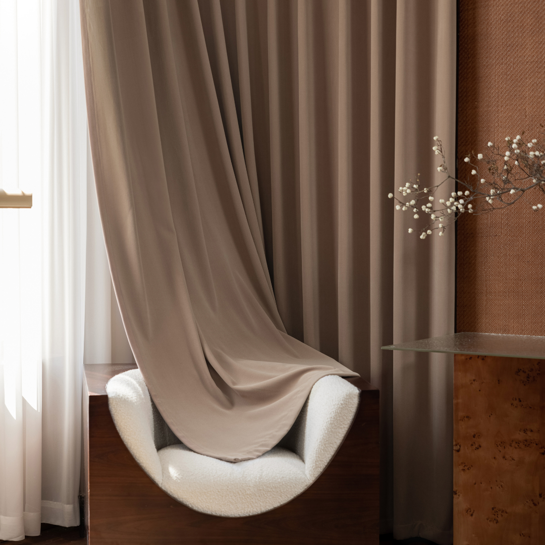 Deep walnut brown blackout curtains in a modern living room with soft armchair and sheer curtain.