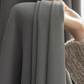Hand holding soft textured graphite ash blackout curtain close up