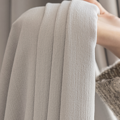 Close-up of textured light grey curtain fabric, ideal for modern home decor.