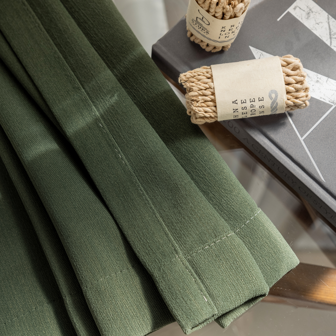 Green textured curtain fabric with rope tiebacks on a glass table