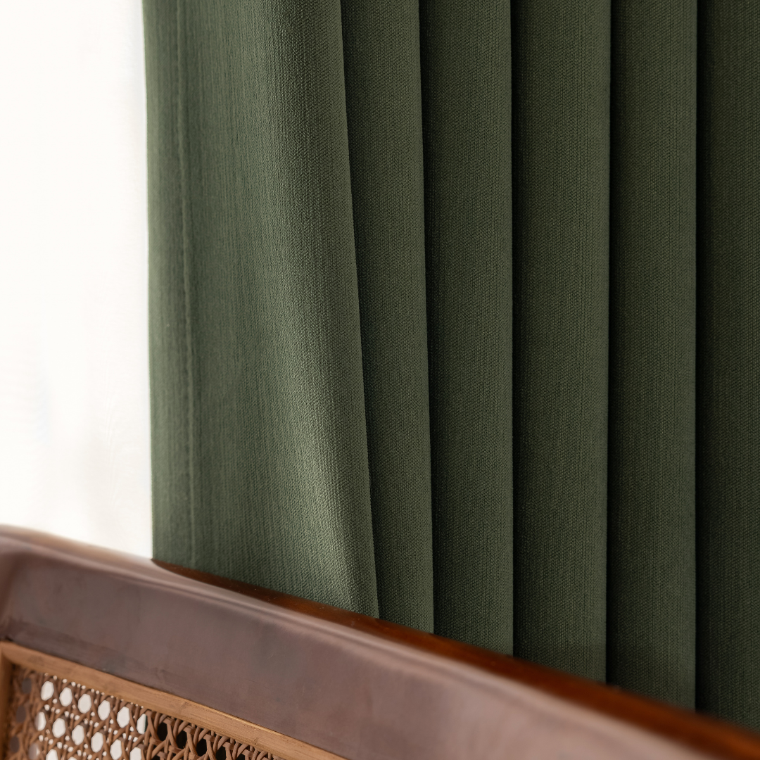 Green blackout curtain with textured fabric behind wooden chair, home decor